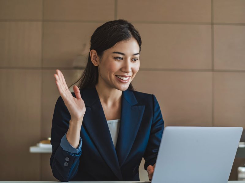 smiling-asian-businesswoman-video-conferencing-laptop-modern-office